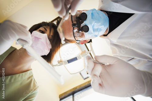 Dentist and nurse towering over patient in office photo