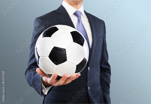 Fototapeta Naklejka Na Ścianę i Meble -  Soccer. Elegant businessman holding a soccer ball, close up