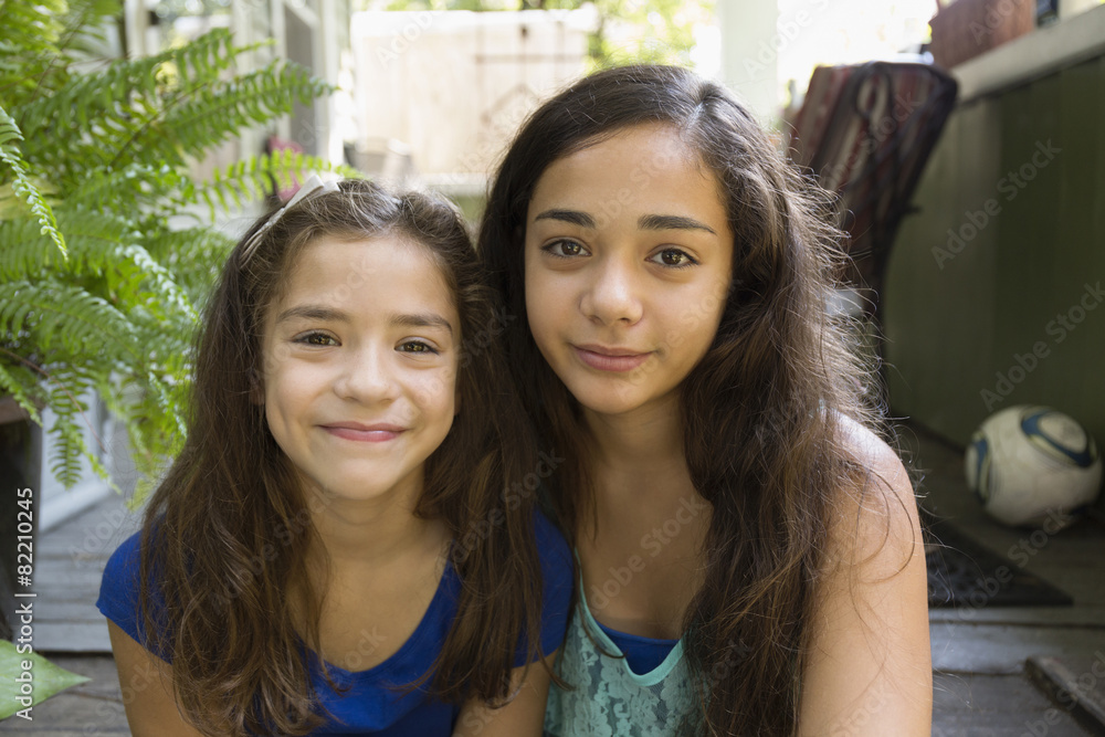 Mixed race sisters sitting outdoors Mixed race sisters sitting outdoors