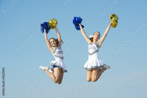 Caucasian cheerleaders jumping in mid-air photo