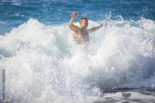 Young man bathing in storming sea, water in focus