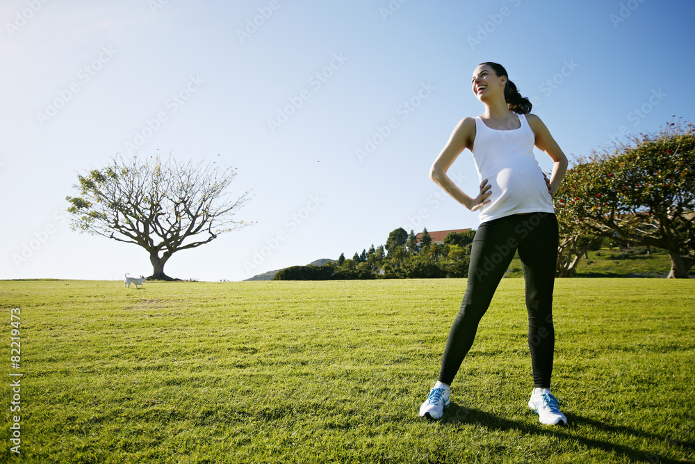 Pregnant mixed race woman standing in field