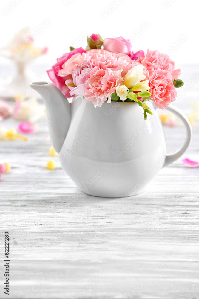 Beautiful spring flowers in teapot on wooden table, closeup Beautiful spring flowers in teapot on wooden table, closeup