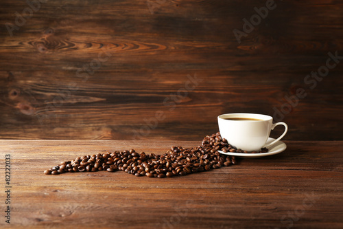 Cup of coffee with grains on wooden background