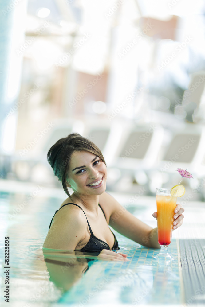 Beautiful lady drinking a cocktail in a swimming pool and relaxi Beautiful lady drinking a cocktail in a swimming pool and relaxi