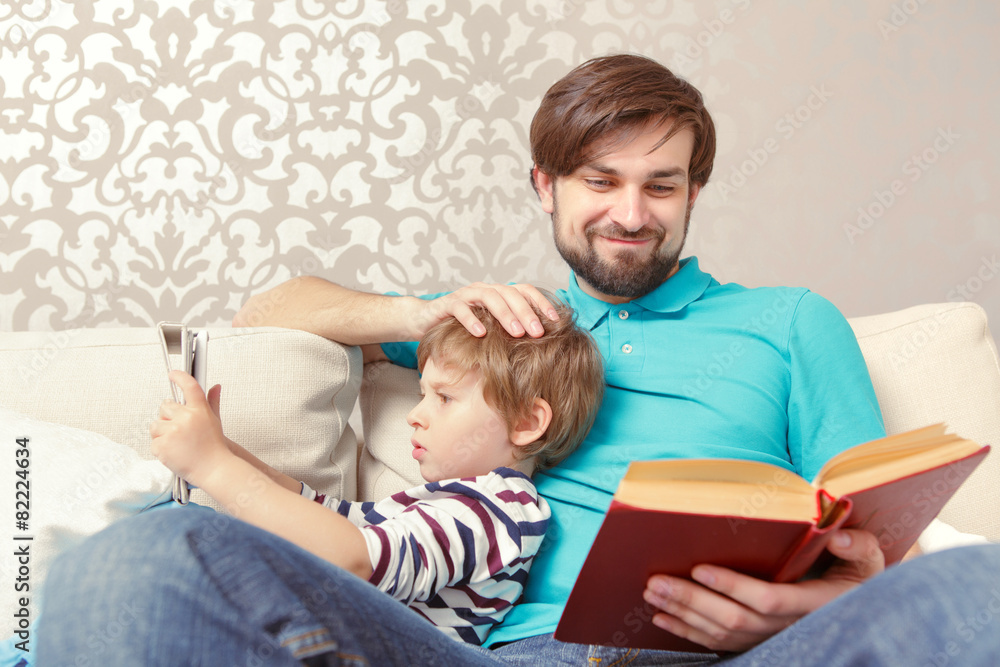 Father and son read a book or tablet Father and son read a book or tablet