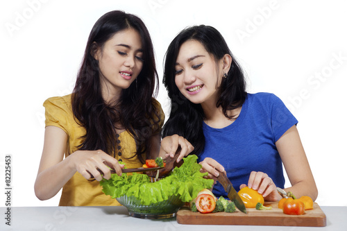Attractive girls preparing vegetables salad