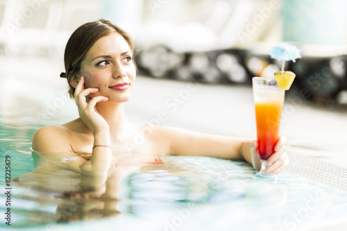 Beautiful young woman drinking a cocktail while in the swimming