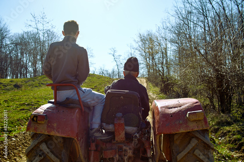 Grandfather and his grandson driving a tractor at sunset