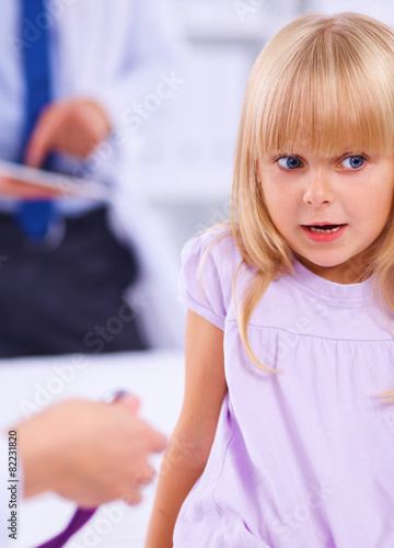 Female doctor examining child with stethoscope at surgery