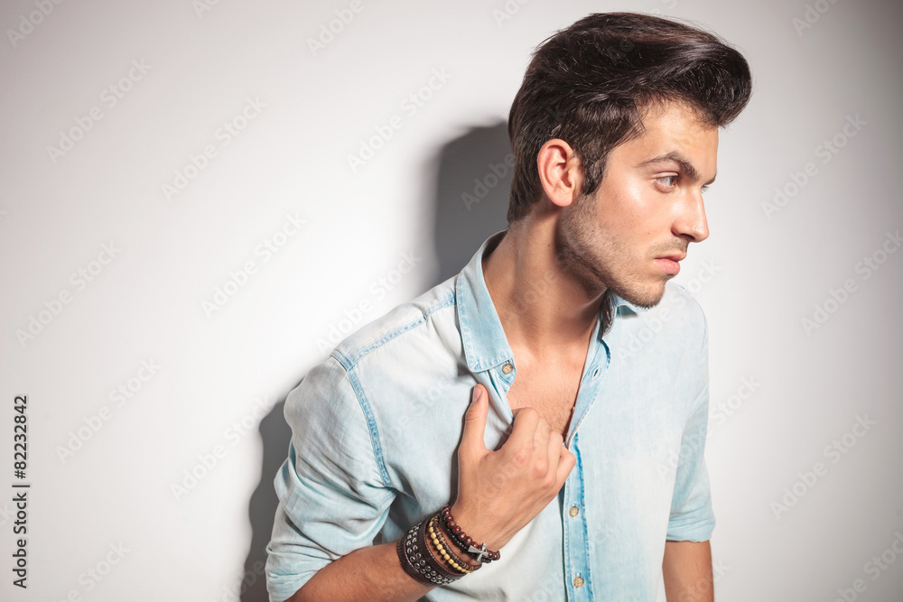 fashion man leaning on a wall while pulling his collar. fashion man leaning on a wall while pulling his collar.