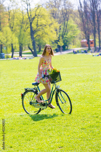 Young woman in short colorful dress with long hair rides a bicyc