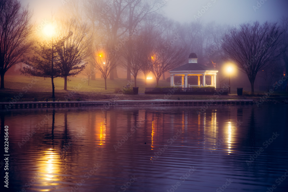 Foggy night scene at pond with lights and gazebo
