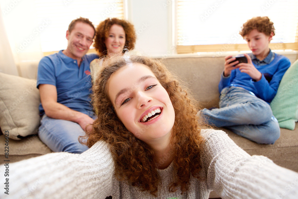 Happy girl taking a selfie with family in background Happy girl taking a selfie with family in background