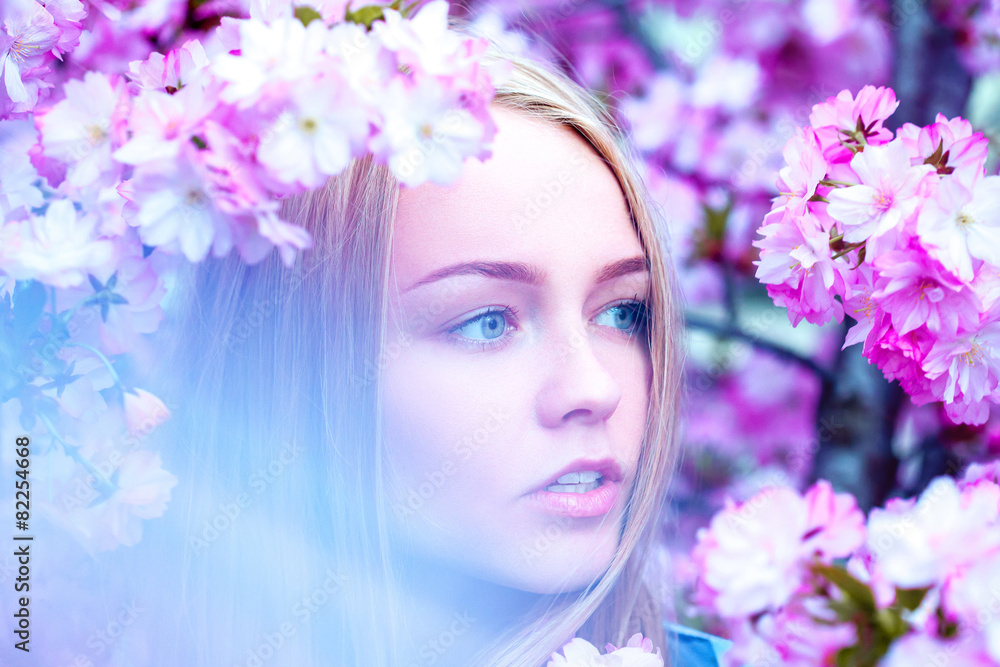 Horizontal portrait of adorable young blonde in blooming flowers