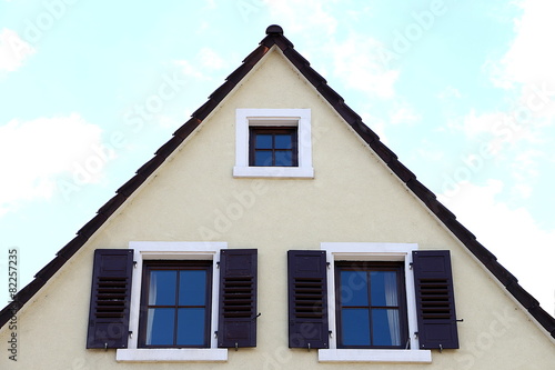 Hausgiebel mit drei Fenstern, zwei mit braunen Fensterläden