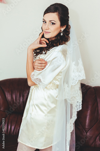 Happy beautiful bride tries on a wedding dress dressing gown