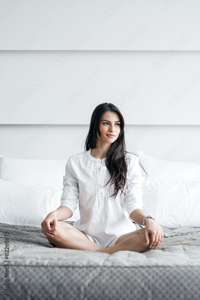 Beautiful brunette in a white shirt tailor seat posing on a bed Beautiful brunette in a white shirt tailor seat posing on a bed