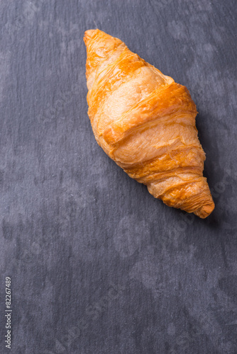 Tasty french croissant on a black stone plate