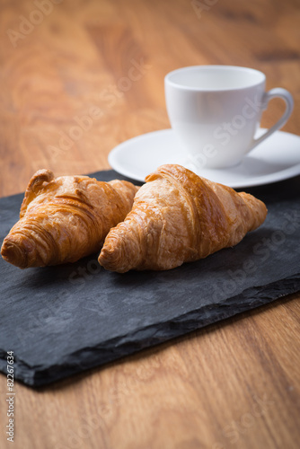 Two tasty french croissants with a cup of coffee