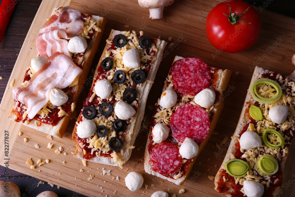 Different sandwiches with vegetables and cheese on cutting board on table close up Different sandwiches with vegetables and cheese on cutting board on table close up