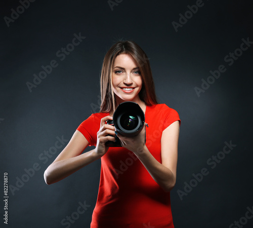 Young female photographer taking photos on black background