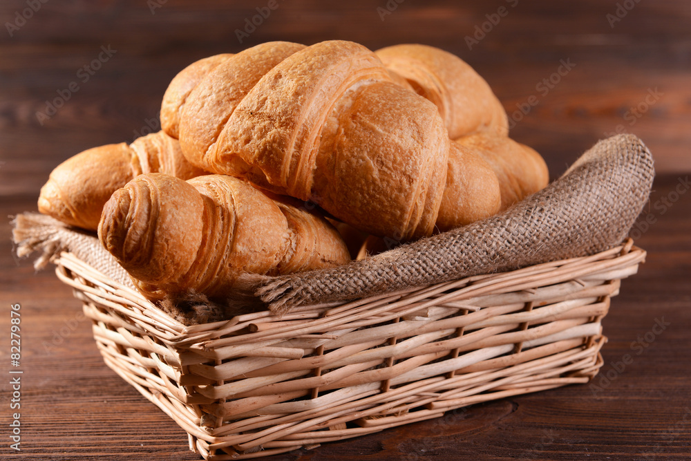 Delicious croissants in wicker basket on table close-up