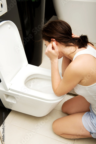 Woman vomiting in toilet.