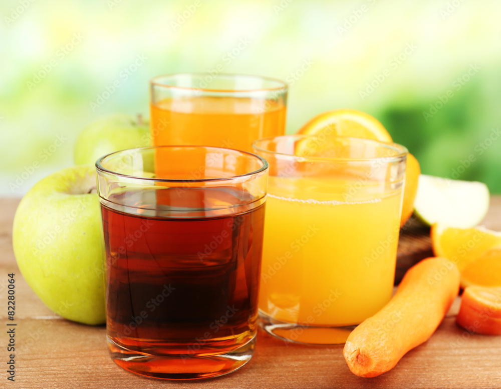 Assortment of healthy fresh juices on wooden table, on bright background Assortment of healthy fresh juices on wooden table, on bright background