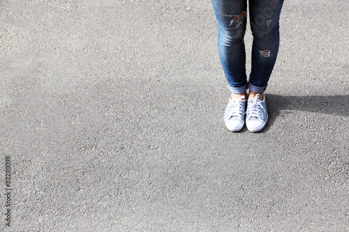 Female feet over gray asphalt background