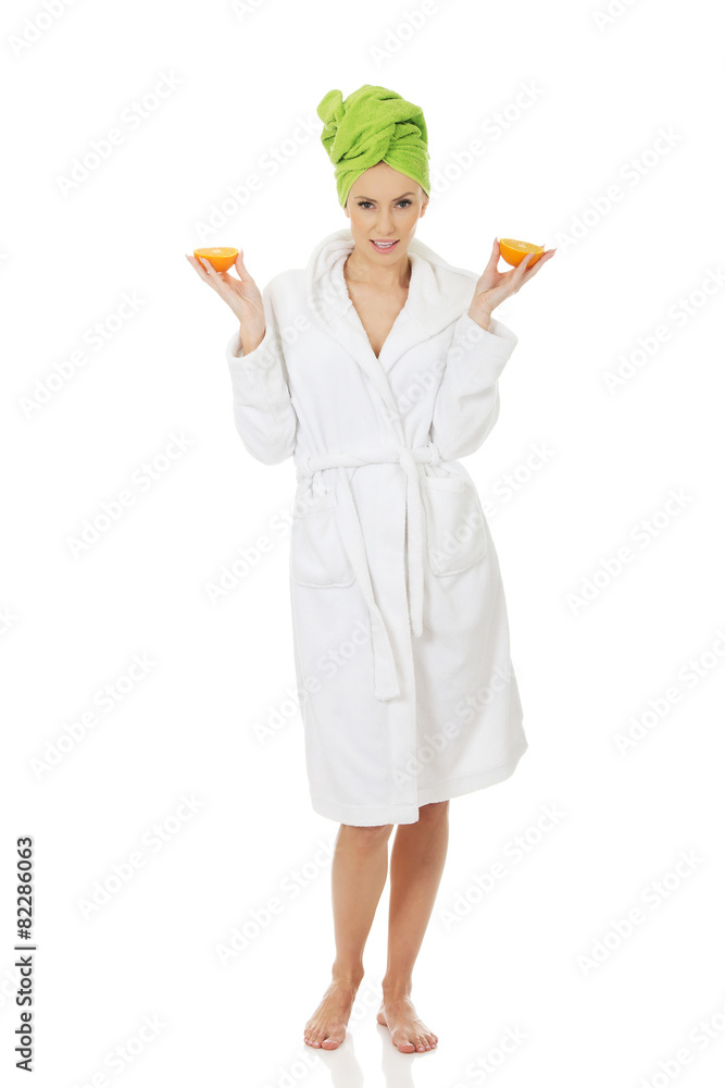 Spa woman in bathrobe holding orange. Spa woman in bathrobe holding orange.
