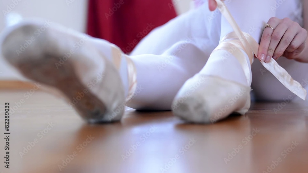 young ballerina preparing for dance - ballerina ties shoes