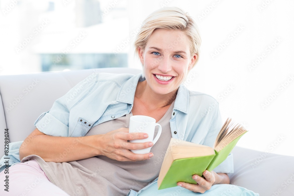 Pretty blonde woman reading a book and holding a mug Pretty blonde woman reading a book and holding a mug
