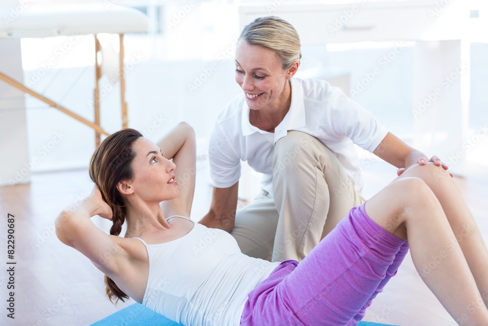 Trainer working with woman on exercise mat Trainer working with woman on exercise mat