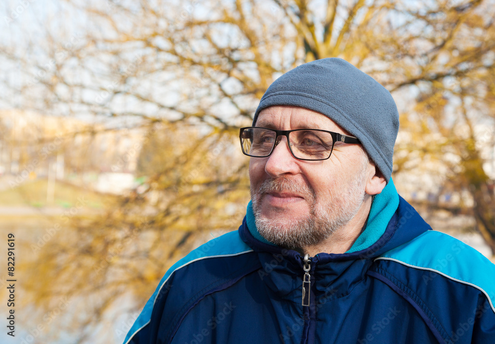 elderly man wearing glasses, a gray hat and blue jacket in a cit elderly man wearing glasses, a gray hat and blue jacket in a cit