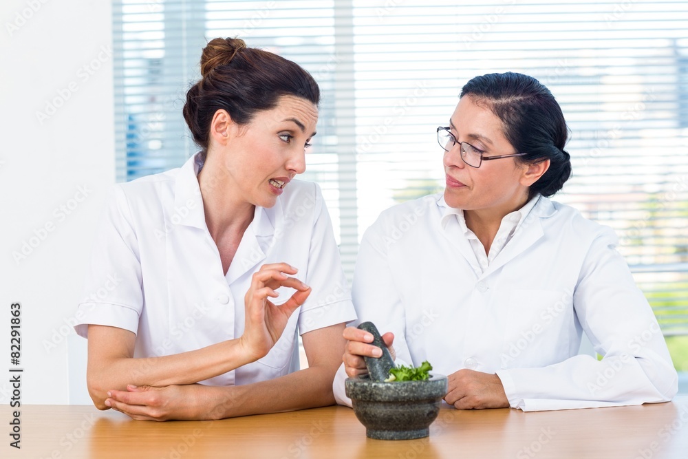 Scientists mixing herbs with pestle and mortar Scientists mixing herbs with pestle and mortar