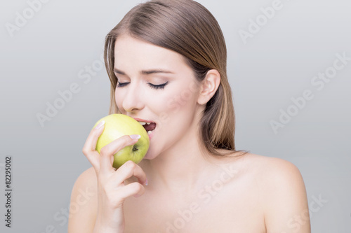 Beautiful woman enjoying green apple on white background