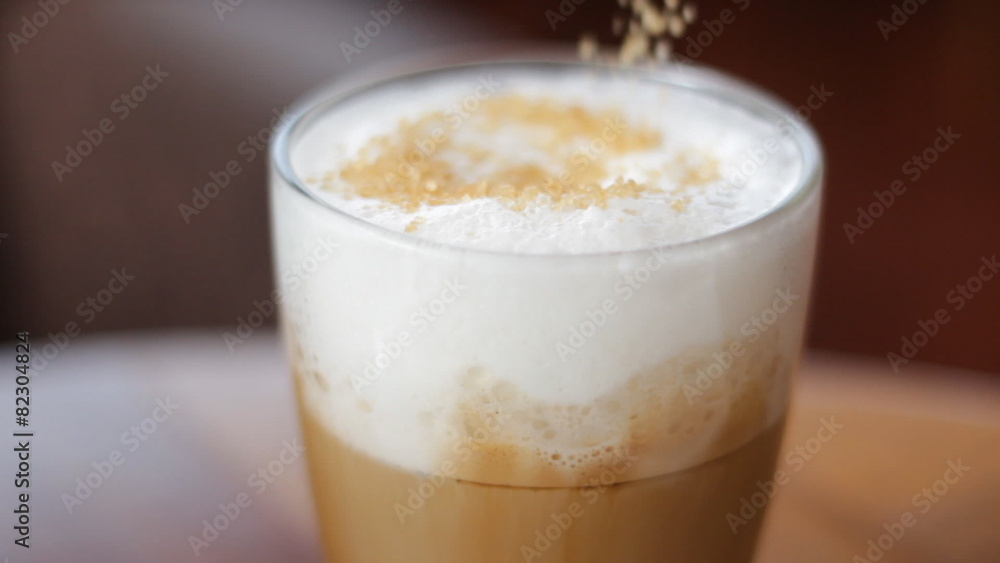 Putting sugar and mixing with a spoon the cappuccino Putting sugar and mixing with a spoon the cappuccino
