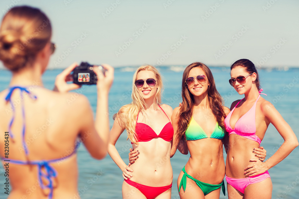 group of smiling women photographing on beach