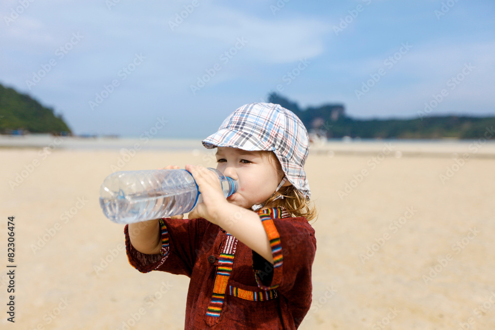 Child on tropical beach, drinking bottled water Child on tropical beach, drinking bottled water