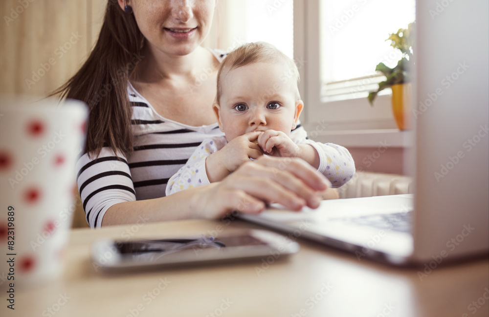 Young mother in home office with computer and her daugher Young mother in home office with computer and her daugher