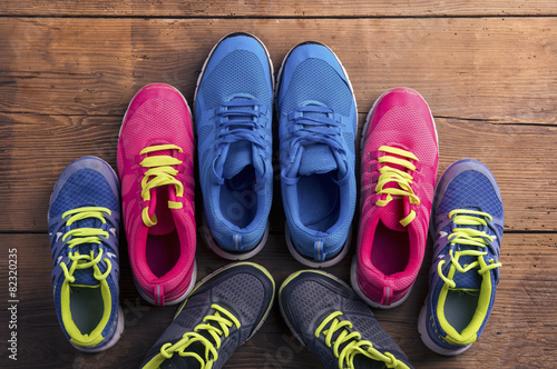Four pairs of various running shoes laid on a wooden background