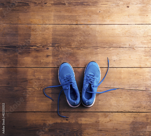 Pair of blue running shoes laid on a wooden floor background