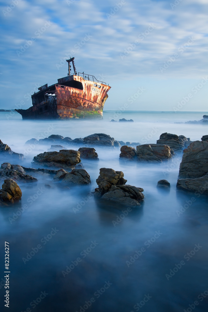 Old shipwreck long exposure on rocks at sunset