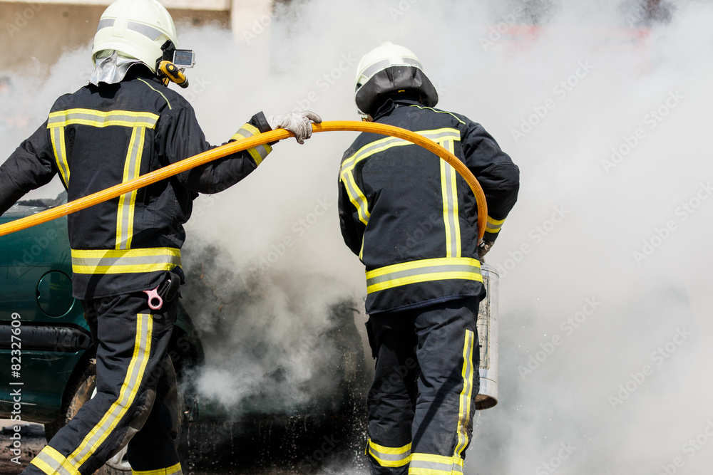 two firefighters putting out a car fire two firefighters putting out a car fire