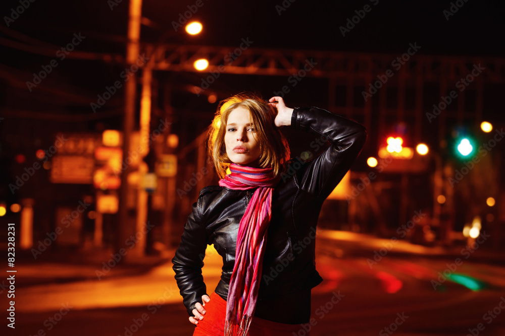 A beautiful glamour girl in jacket is standing in the city stree