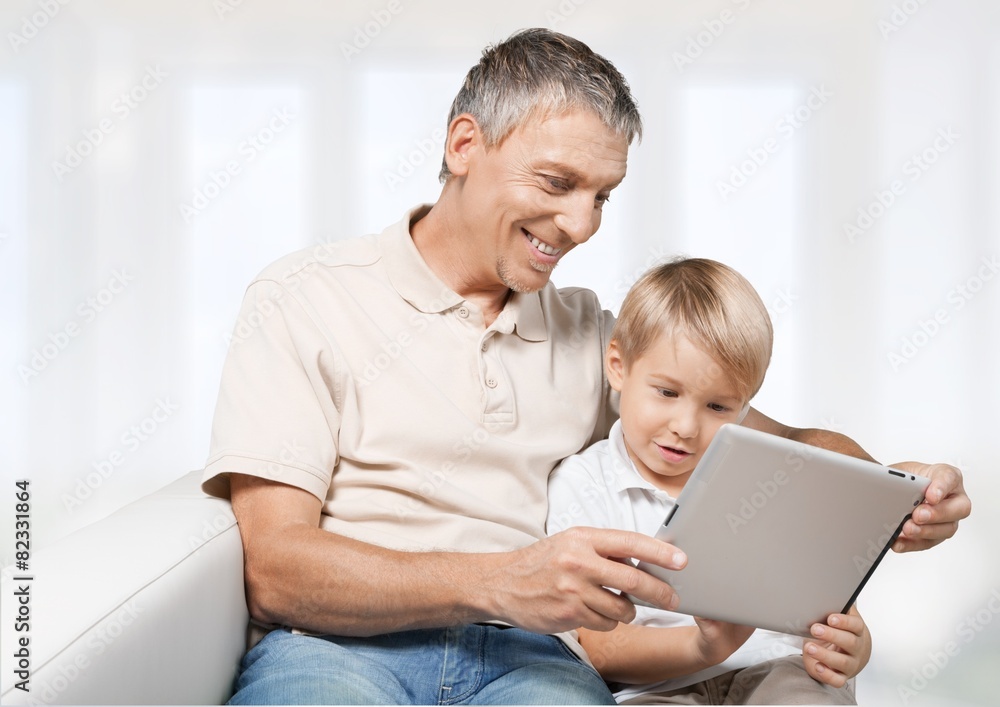 Father. Overhead View Of Father And Son On Sofa Using Digital Father. Overhead View Of Father And Son On Sofa Using Digital