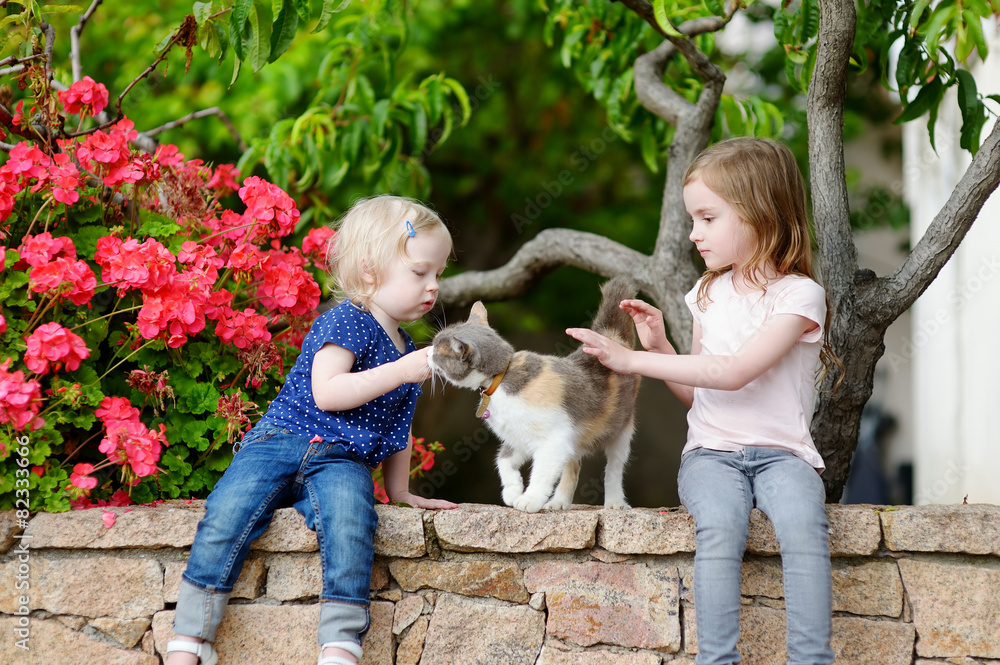Fototapeta premium Two cute little sisters and a cat