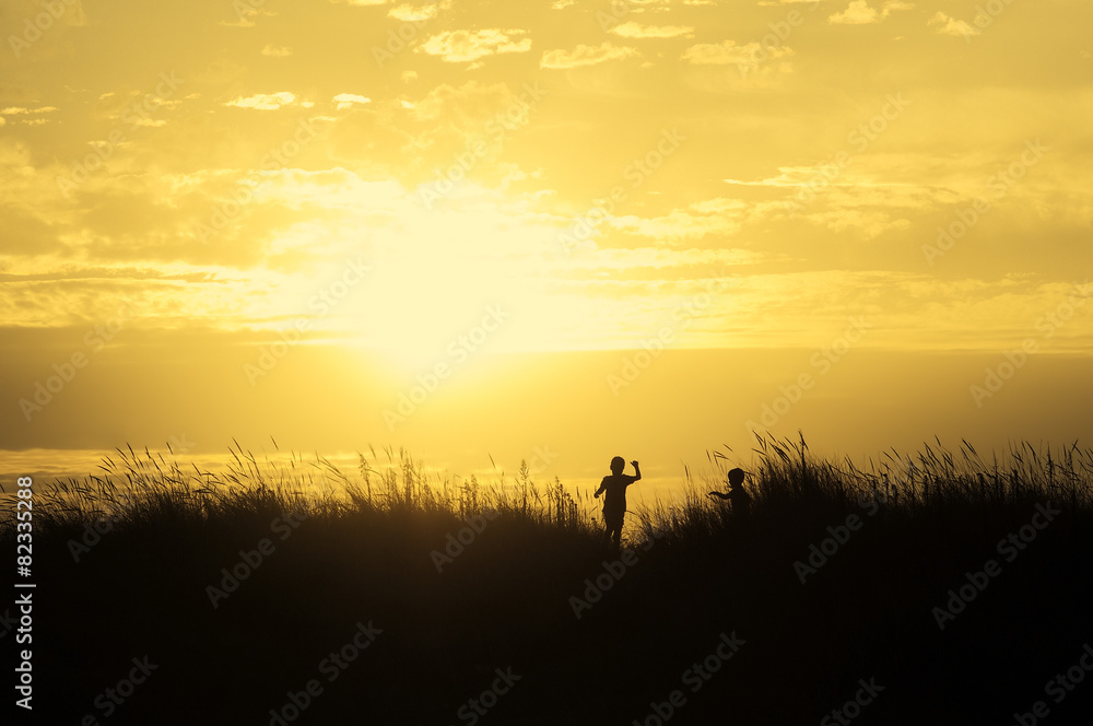 children playing on beach dunes at sunset silhouette