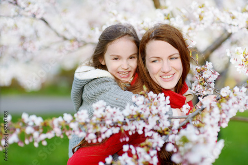 Mother and her child in blooming cherry garden